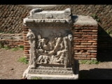 02084 ostia - regio ii - insula vii - sacello dell'ara dei gemelli (ii,vii,3) - altarstein romulus und remus - hier vor ort vorderseite - romulus und remus und die woelfin - hirten - re unten flussgott.jpg